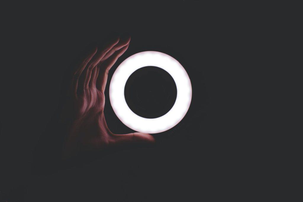 Hand hält leuchtenden LED-Ring in der Dunkelheit, symbolisiert agiles Projektmanagement.